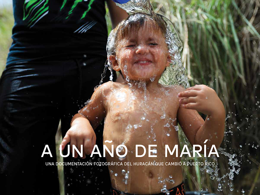 Child receiving a bath from a bucket of water outdoors on the cover for A un año de María, a photo book by photojournalists from El Nuevo Día of life in Puerto Rico after Hurricane María